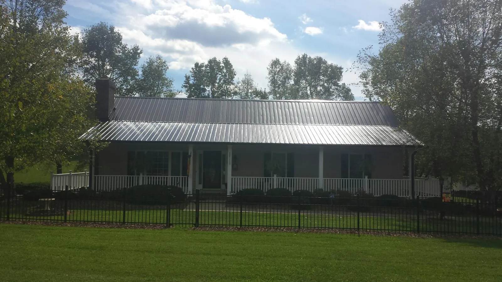 Gray metal roof on a brick ranch with a full width front porch — Gutter Guard Installation work by our crew in Greensburg